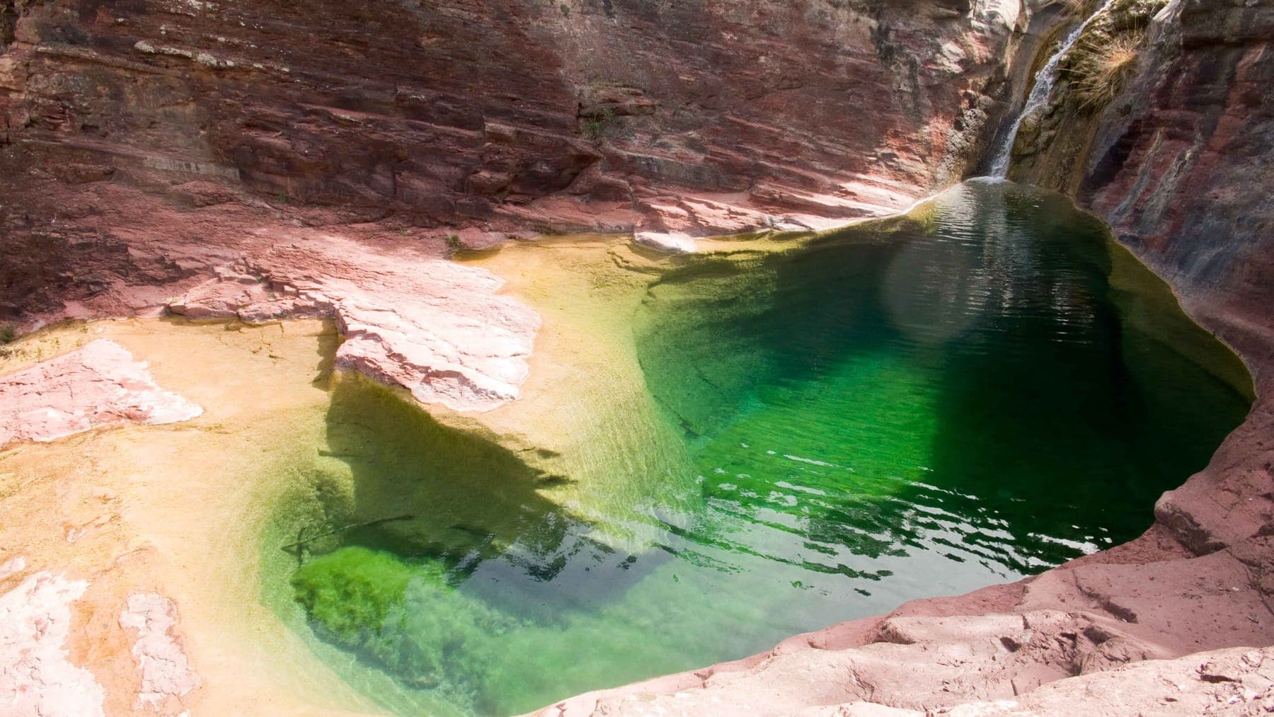 Vista panorámica del Pozo Negro con el agua verde y la roca roja alrededor